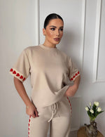 Savršen spoj udobnosti i trendi dizajna – ovaj ženski komplet sa srcima je idealan izbor za svakodnevni outfit. Majica jednostavnog kroja u kombinaciji sa pantalonama koje imaju upečatljiv detalj srca daje moderan i razigran izgled. Mekan i prijatan materijal omogućava maksimalnu udobnost, dok relaxed fit kroj pruža slobodu pokreta.

Ovaj komplet je savršen za opuštene dane, šetnje, putovanja ili casual kombinacije uz minimalan trud.